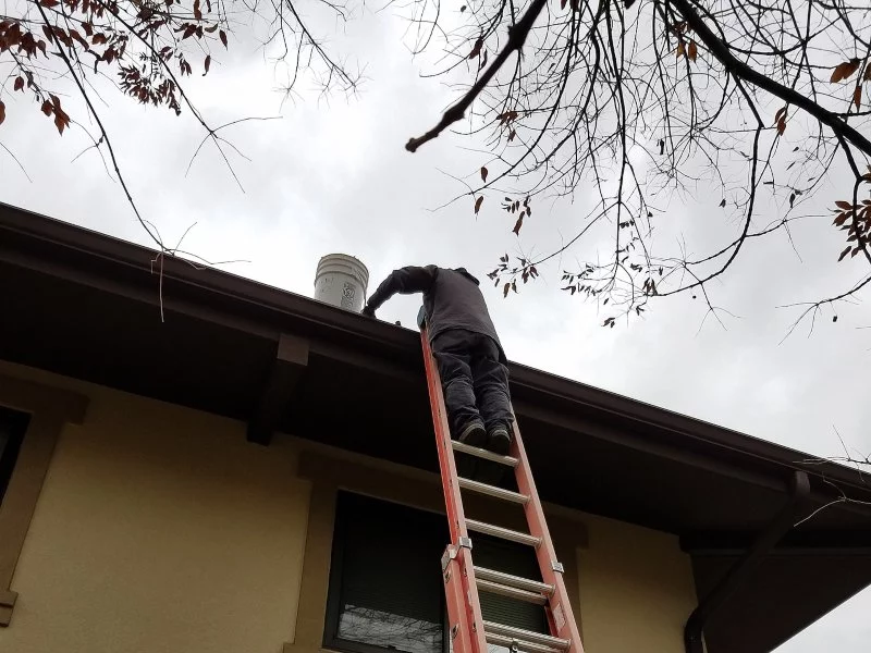 Demarks professional on red ladder cleaning gutter