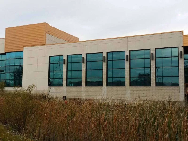 beige and brick building with windows and tall grass