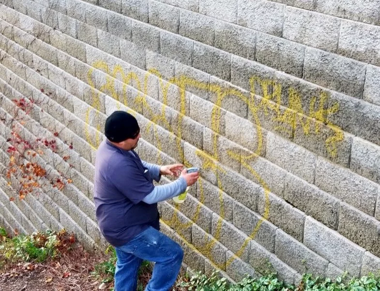 Demarks professional removing graffiti from gray brick wall