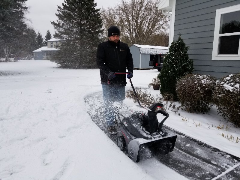 Demarks professional removing snow from walkway